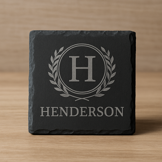 Slate coaster with engraved 'HENDERSON' and monogram on a wooden surface